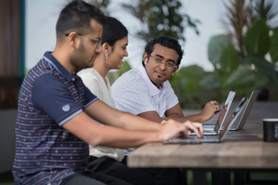 Jóvenes trabajan juntos frente a computadoras portátiles