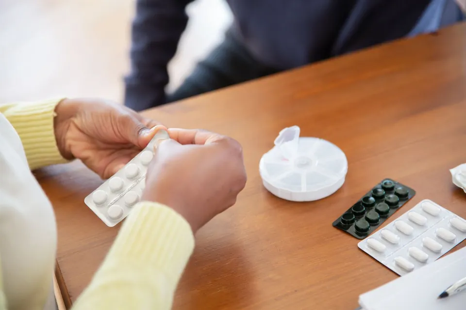 Una persona organiza pastillas en un pastillero semanal