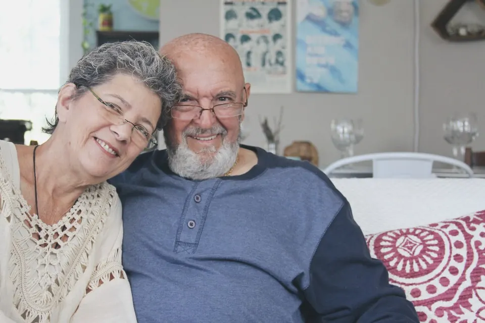 An older couple smiles in an embrace at home